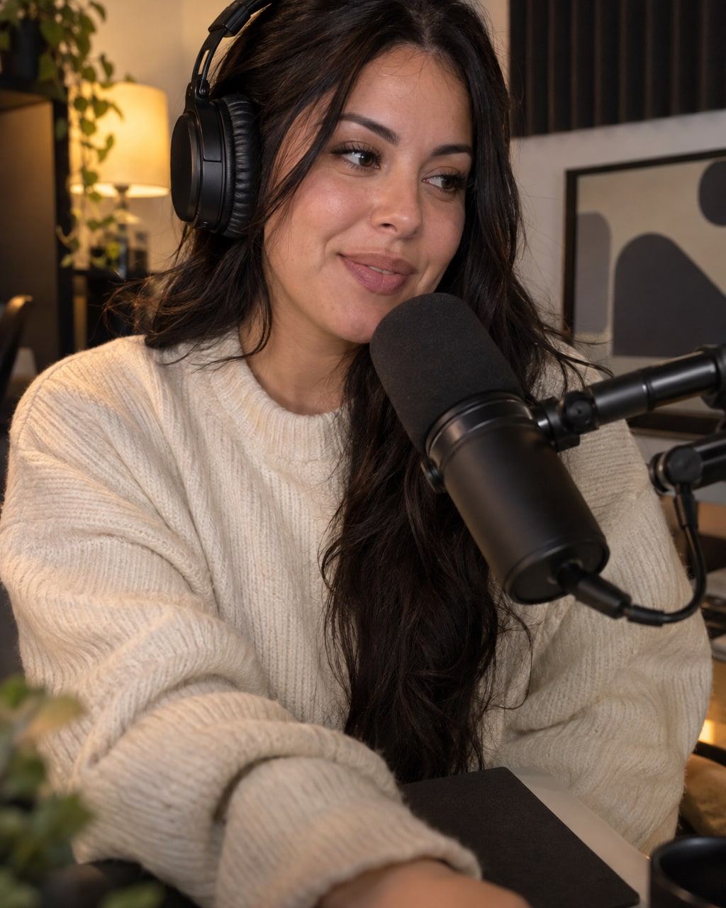 Woman with long dark hair and headphones speaks softly into a studio microphone.